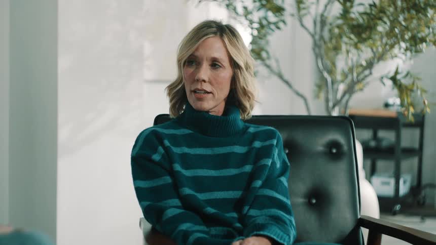 Woman seated in an armchair participating in a conversation indoors