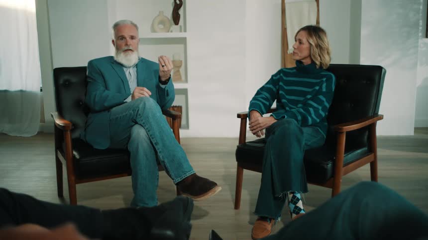 Man and woman sitting in chairs as the man talks