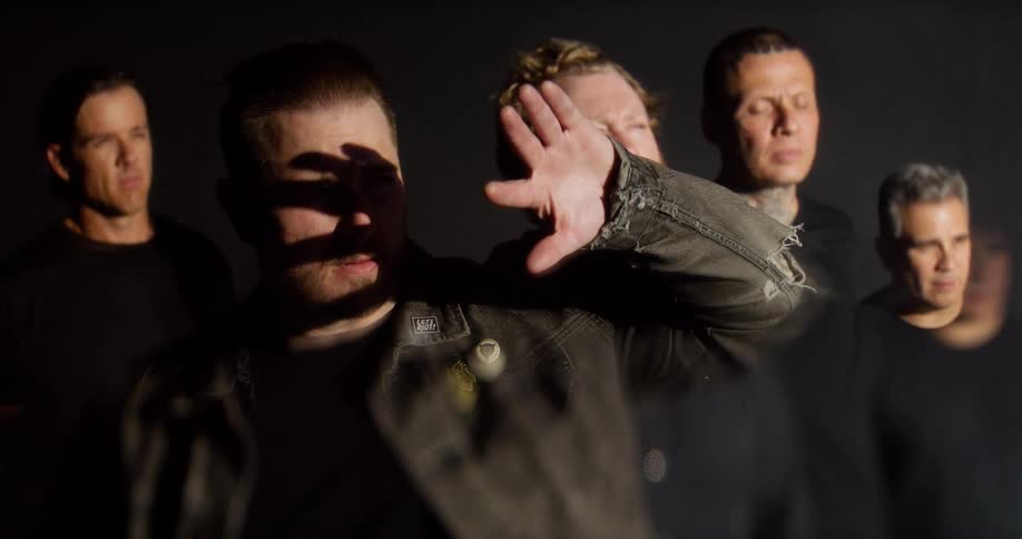 Group of men in a dark studio with one raising his hand in front of the light