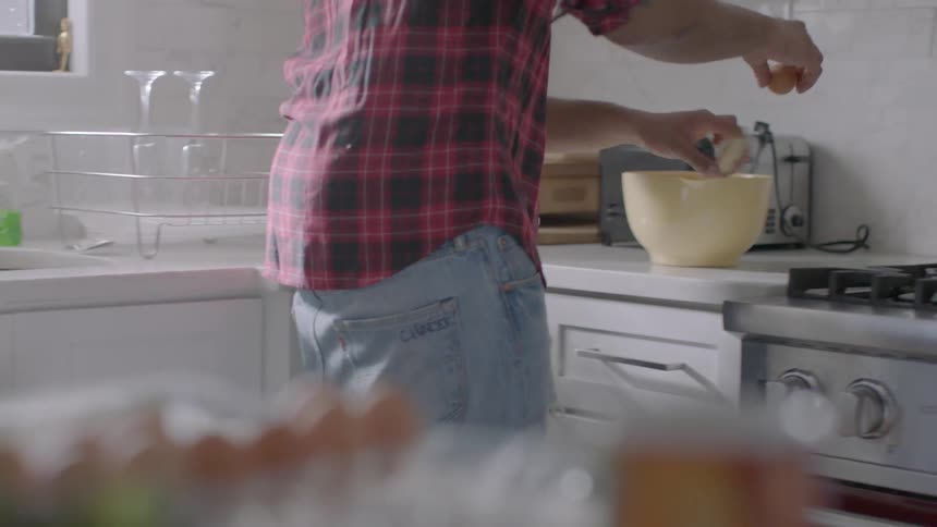 A man is mixing eggs in a large bowl