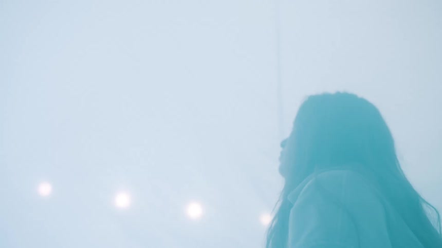 Person in profile surrounded by diffused light and fog in an indoor setting