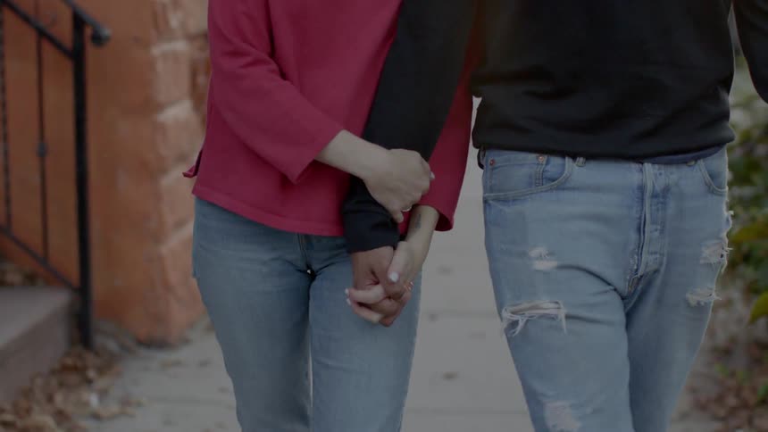 A man and woman walk down the sidewalk