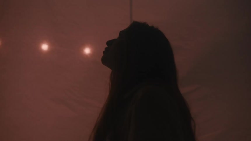 Woman in profile observing diffused light in an environment with white curtains