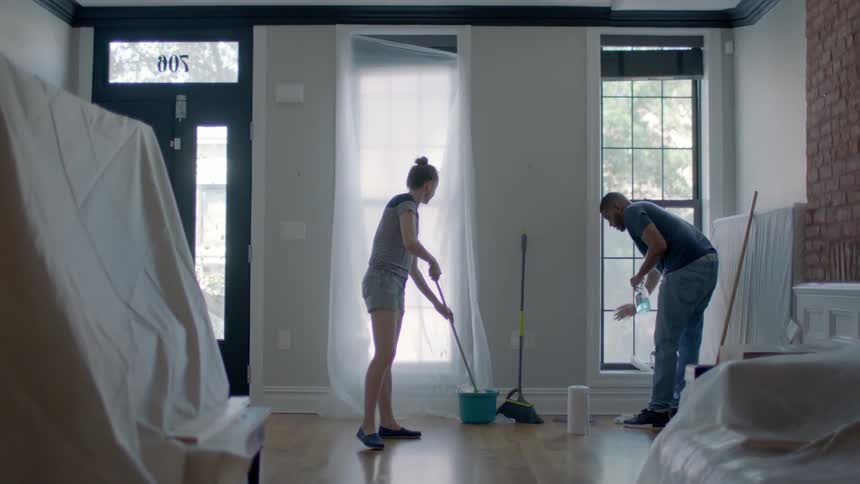 A man and woman clean up a living room