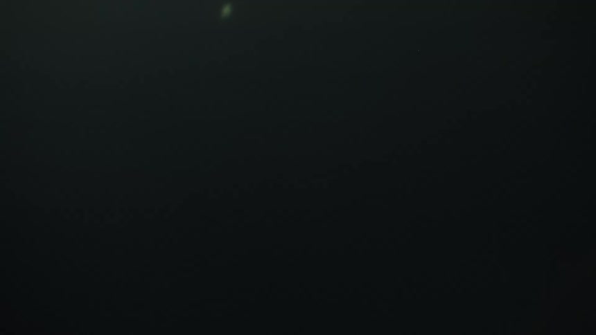 A woman with long dark hair reaches out toward a large white fabric sheet her movements obscured by thick fog and shifting cinematic lighting the scenes transition between warm orange glares moody teal shadows and abstract closeups of light reflectin
