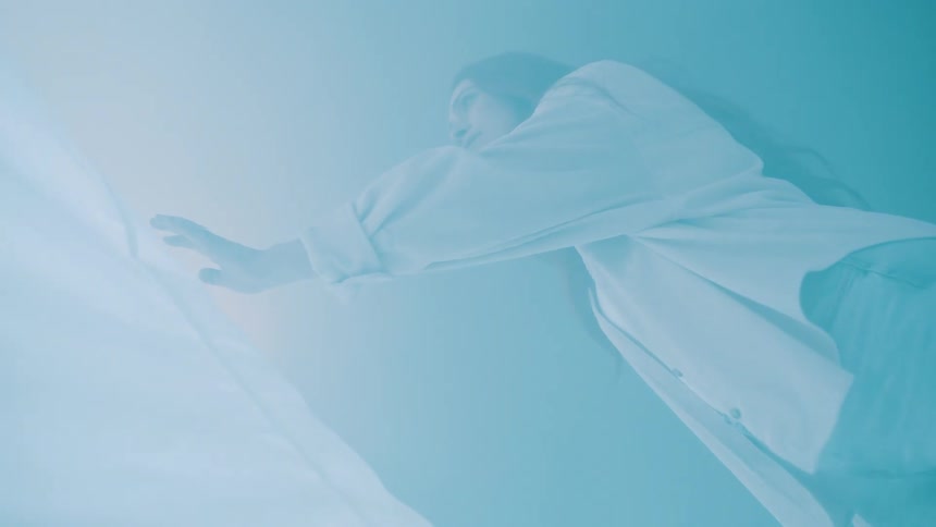Woman leans forward with outstretched arm under bluish light on fabric
