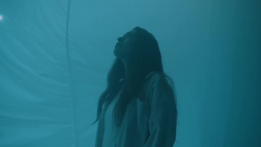 Woman in profile looks up against a softly lit warm translucent backdrop
