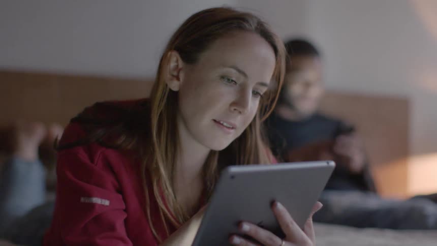 A man and woman use their devices in bed