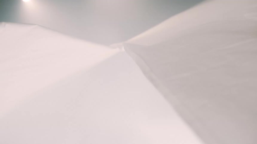 White fabric folds forming smooth surfaces under diffused lighting