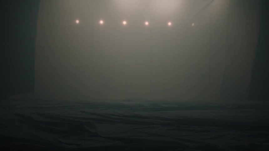 Empty space with dark floor and a row of suspended lights in a foggy environment