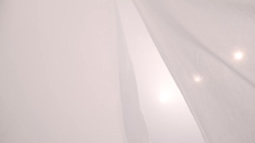 White curtain fluttering indoors in a room with a row of spotlights
