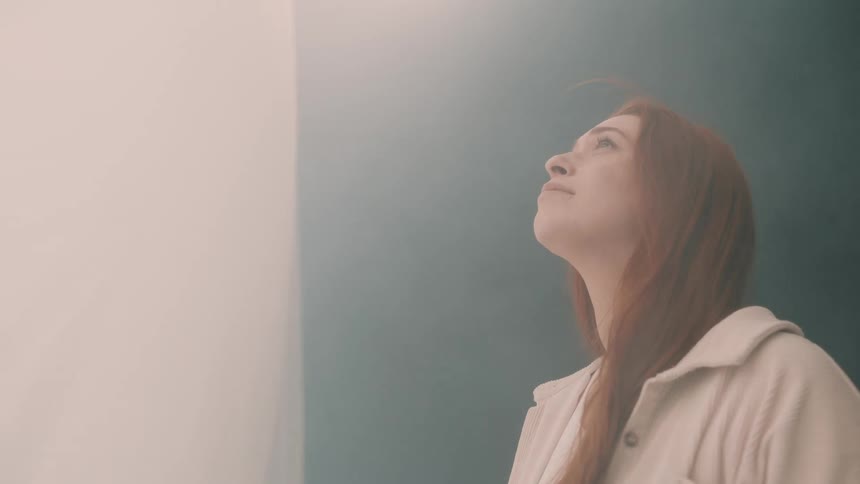A young woman stands inside a large tent wearing a jacket her long hair falling loosely around her shoulders