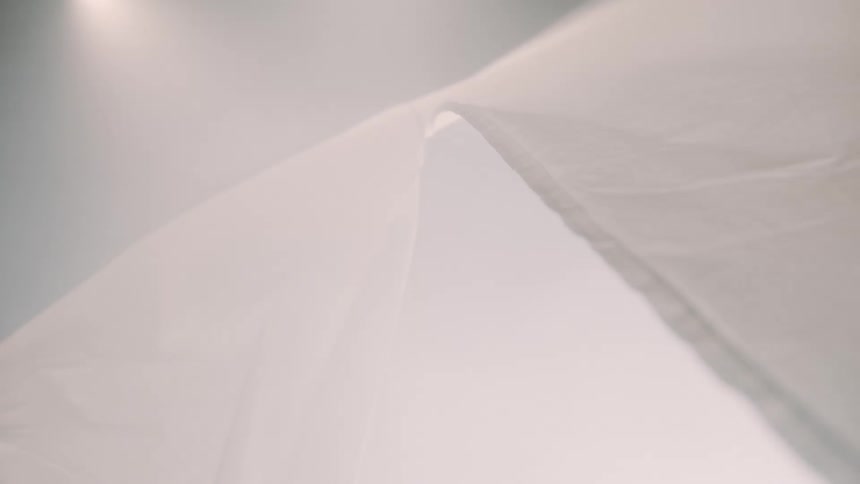 White fabric folds creating soft volumes under diffused lighting