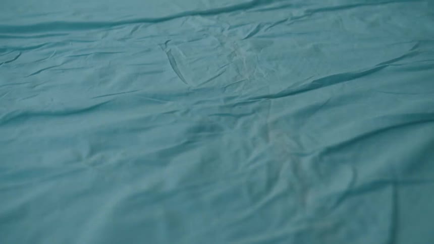 A close up shot shows a wrinkled dark blue fabric surface