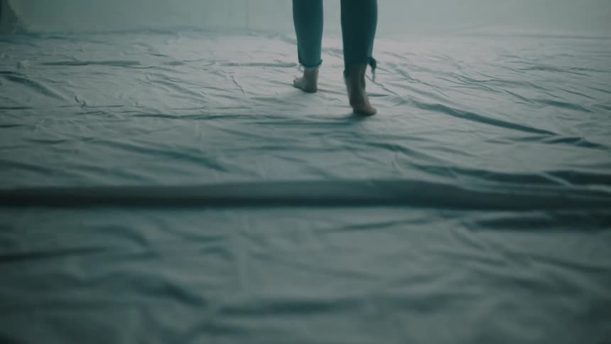The woman walks over the sheets covering the floor