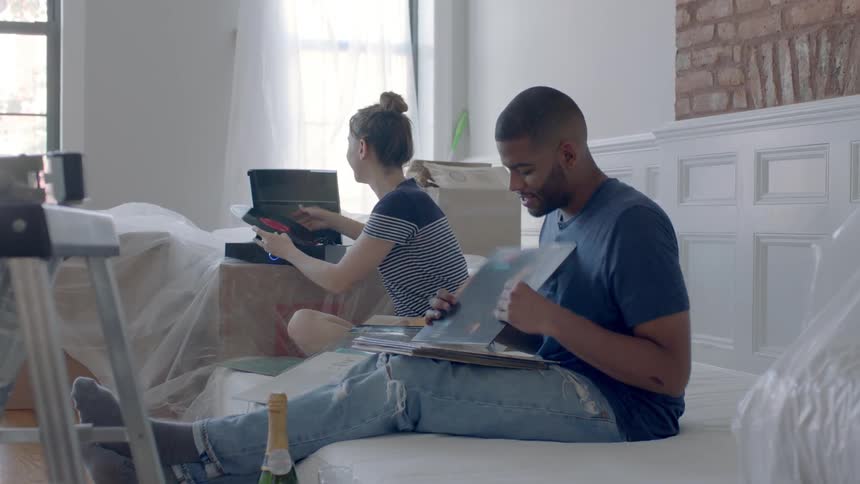 Man and woman sit on a couch looking through records