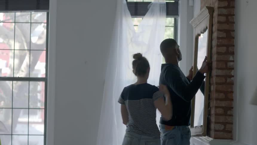 A man lifts up a mirror to put on the wall