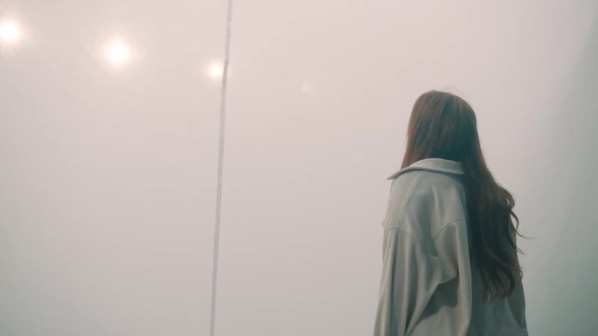 A young woman stands inside a large tent wearing a jacket her long hair falling loosely around her shoulders