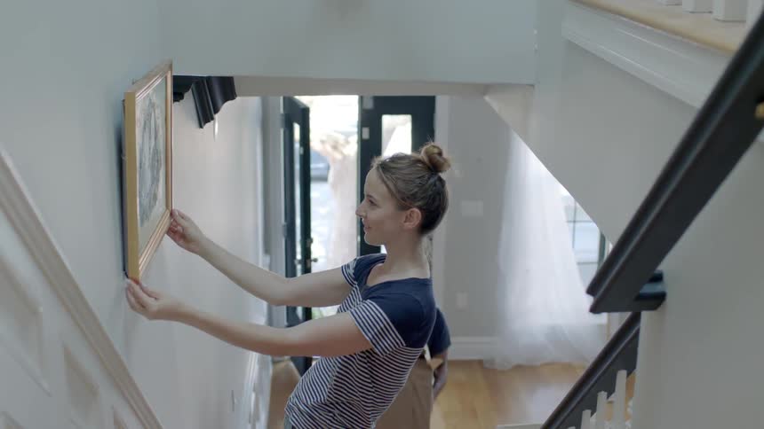 A woman hangs up a painting