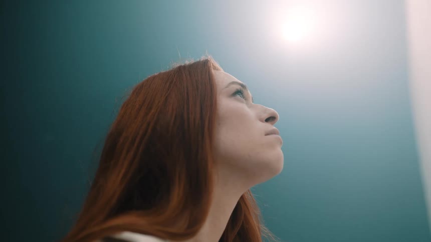 Closeup face of a blonde lady looking up while standing outdoor in the morning