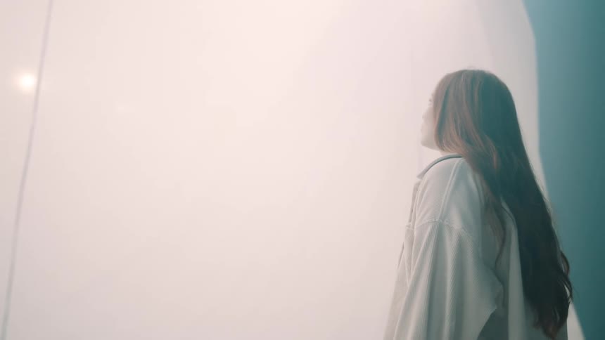 Woman standing and observing white fabric lit in a foggy environment