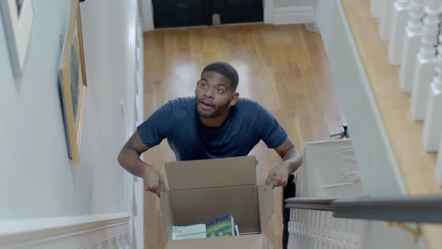 A man carries a cardboard box up stairs