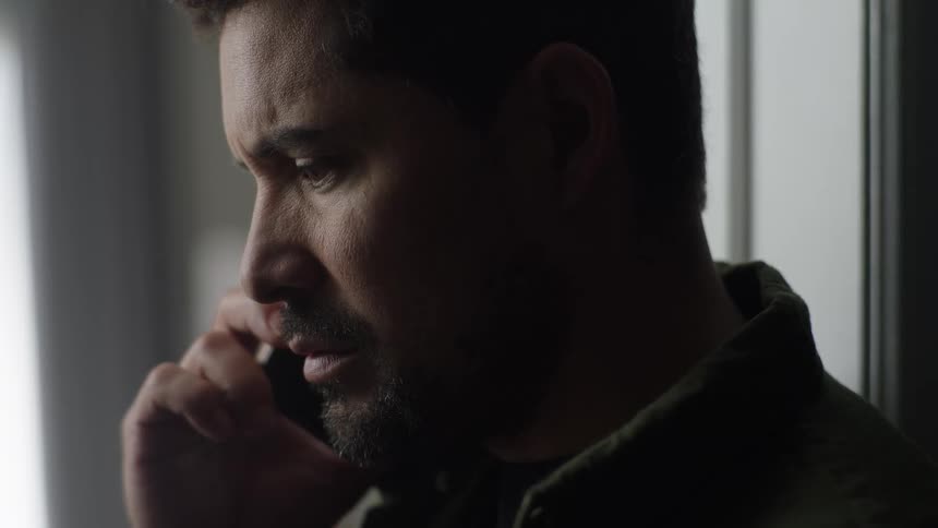 Man speaks on the phone near a window with soft side lighting
