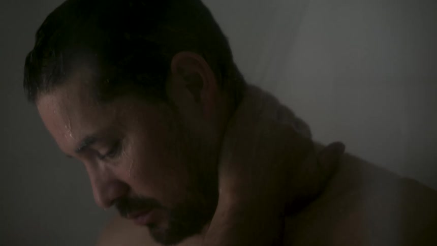Man showering with water running down his face in an indoor environment