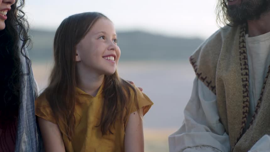 A middle eastern girl nods her head and smiles while seated near Jesus