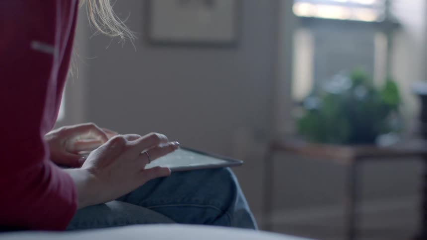 Person sitting on a couch looks at a tablet