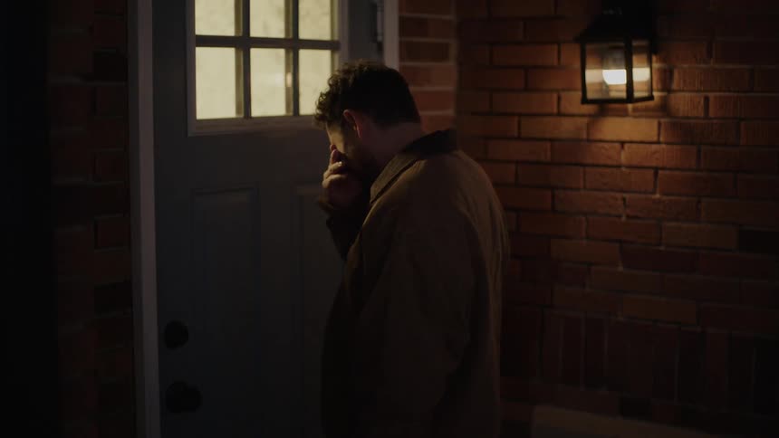 Man opens the house door at night after standing outdoor contemplating for a while