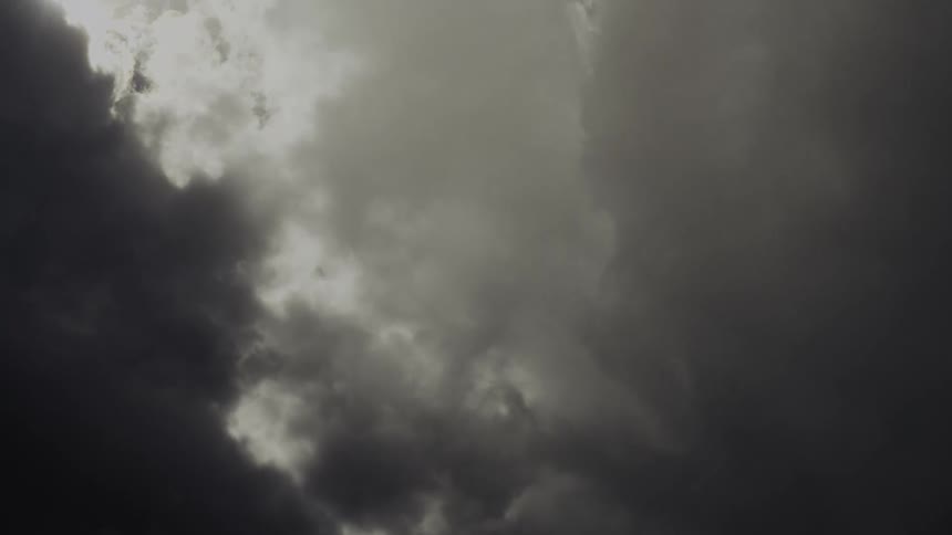 Dark storm clouds swirl and part in a dramatic sky creating a moody atmosphere overhead
