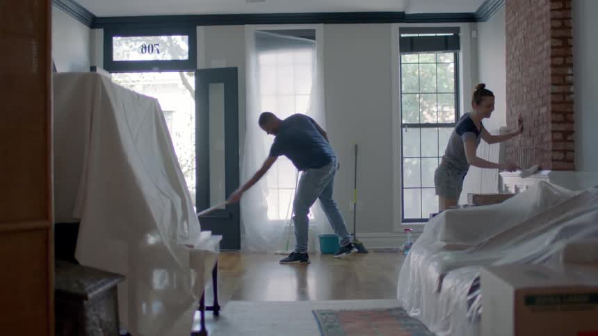 A man mops the floor while a woman scrubs the fireplace