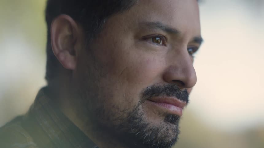 Closeup of a man gazing downward thoughtfully with a calm introspective look in soft natural light