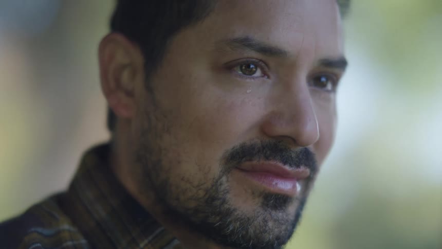 Closeup of a sad man crying quietly with tears in his eyes in soft natural light