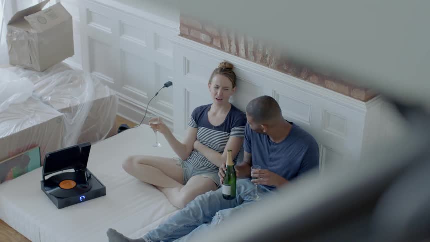 Man and woman sitting on bed are talking and drinking champagne