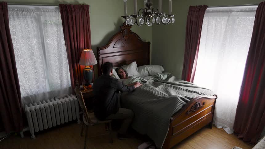 The man holds the sick womans hand in bed