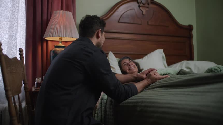 Mother and son share a tender emotional moment holding hands in a quiet bedroom