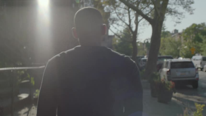 Man walking on neighborhood sidewalk on sunny day