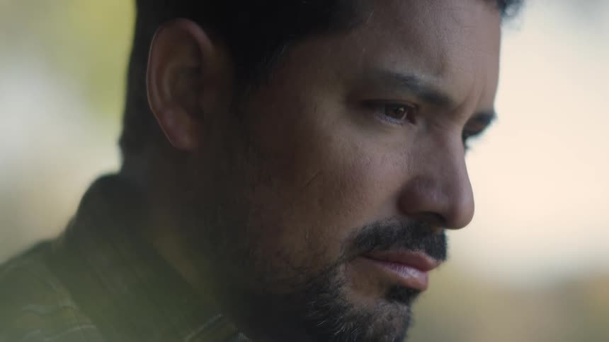 Closeup of a sad man sitting and gazing thoughtfully in soft natural light