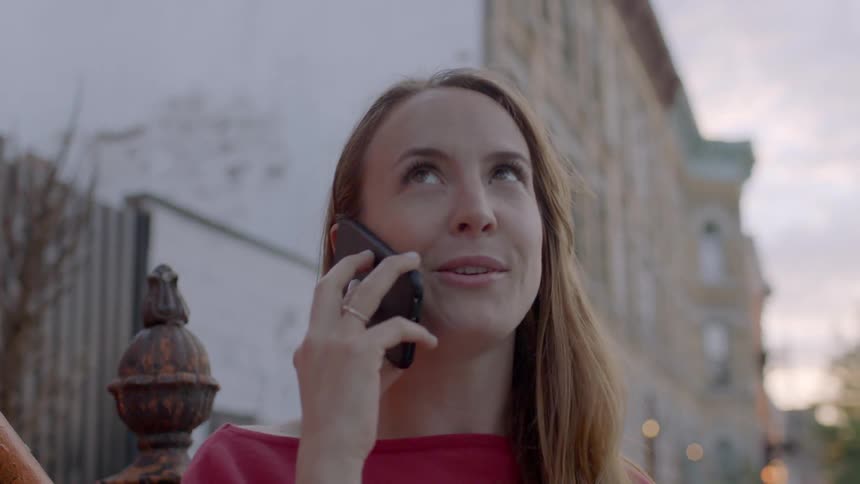 A woman talks on the phone on a city sidewalk