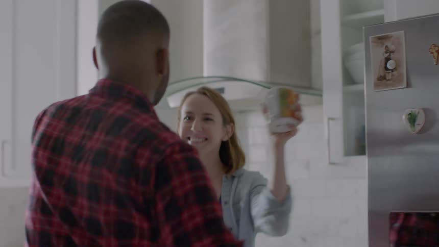 A man and a woman dancing around in their kitchen