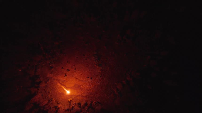 Bright light on rocky terrain seen from above at night
