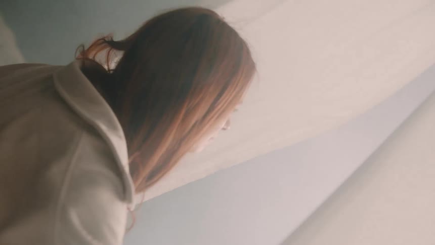 A young woman walks into a tent pulling the linen apart as she steps inside the air around her thick with white smoke