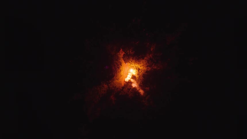 A view of a fire burning outdoors at night