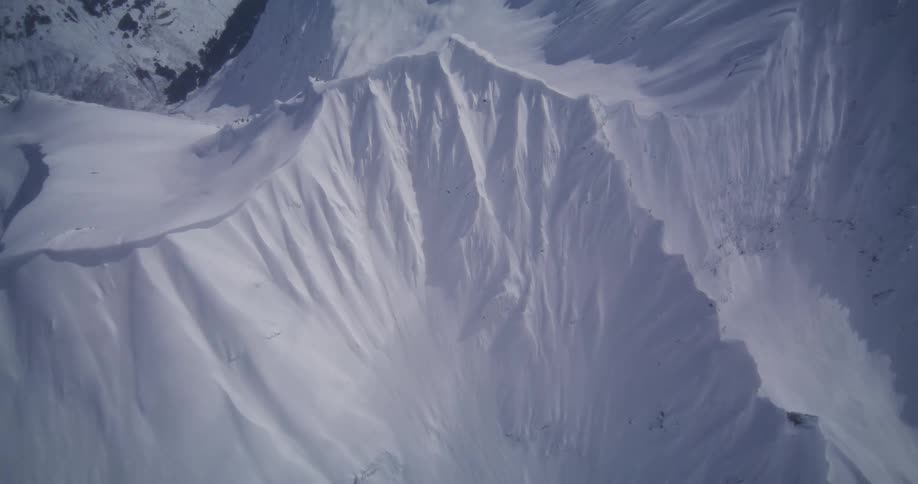 Snow formation with steep ridges seen from above in an alpine environment