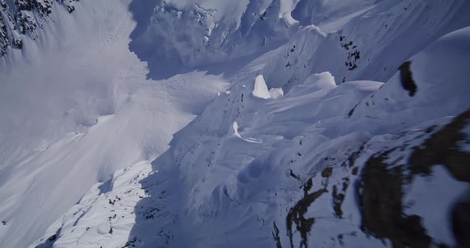 Aerial footage of a snow covered mountain range and its cliffs and slopes