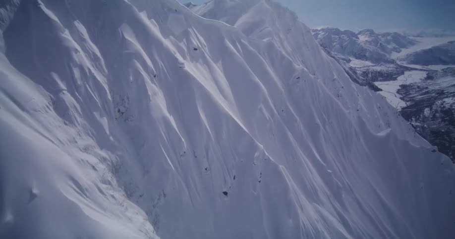 Sunlight shines on the rough terrain of a snow covered mountain range