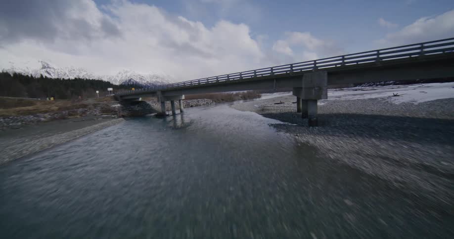 An aerial view of a river with a bridge above it