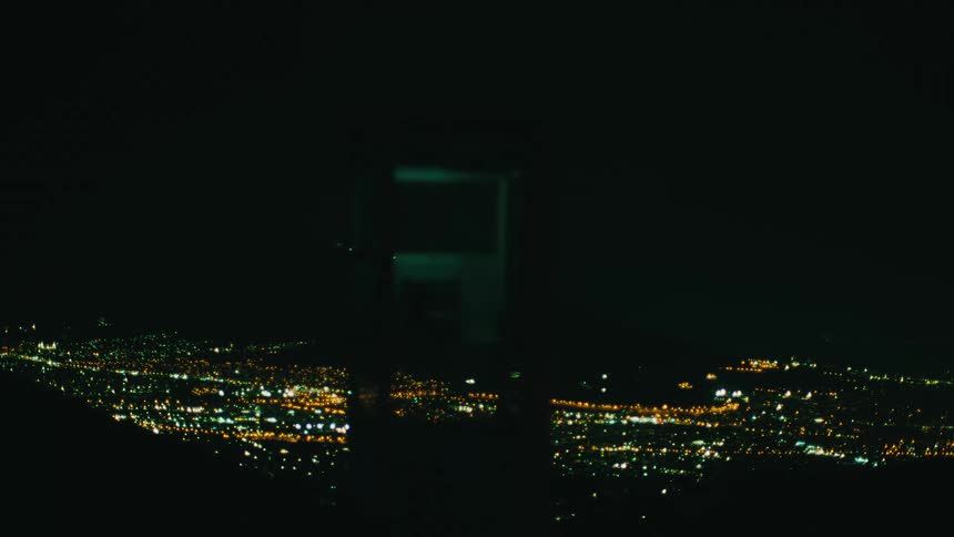 Illuminated structure in the foreground with scattered city lights in the background at night